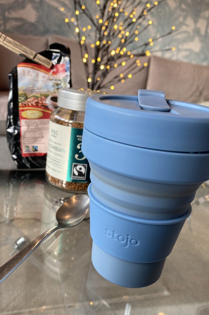 A Blue collapsable coffee mug and silver spoon
