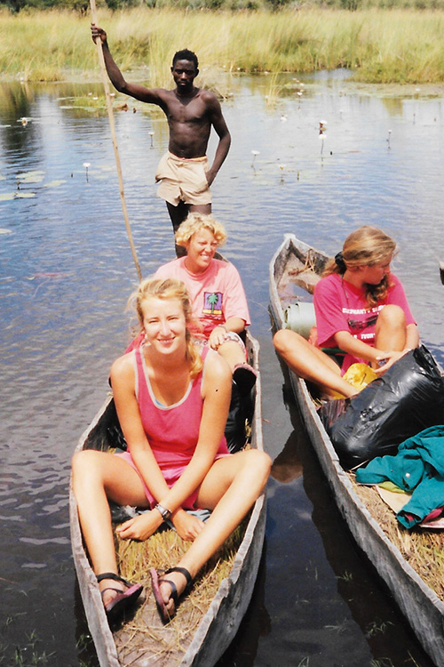 3 Young Women sat in small canoes on an African river