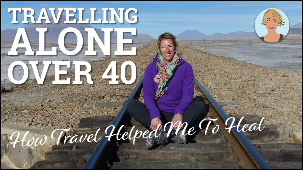 A blonde woman in a purple top sitting on a train track in a remote landscape