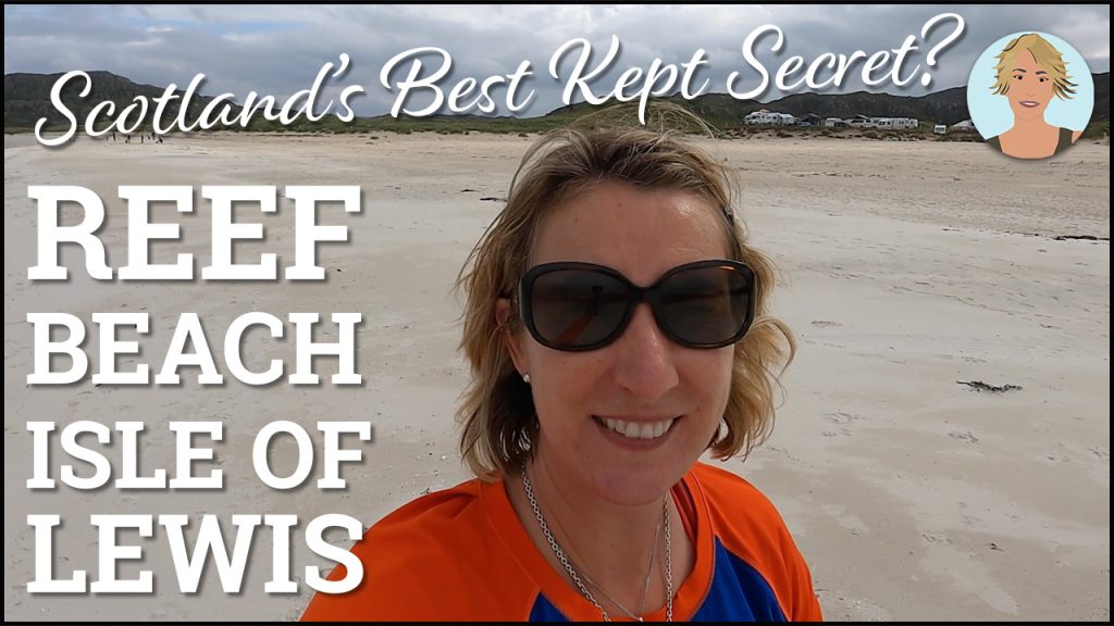 A Woman in sunglasses walking on a sandy beach in an orange top