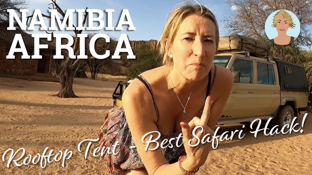 A blonde woman standing in a sandy setting in front of a big yellow jeep in the afternoon sunshine