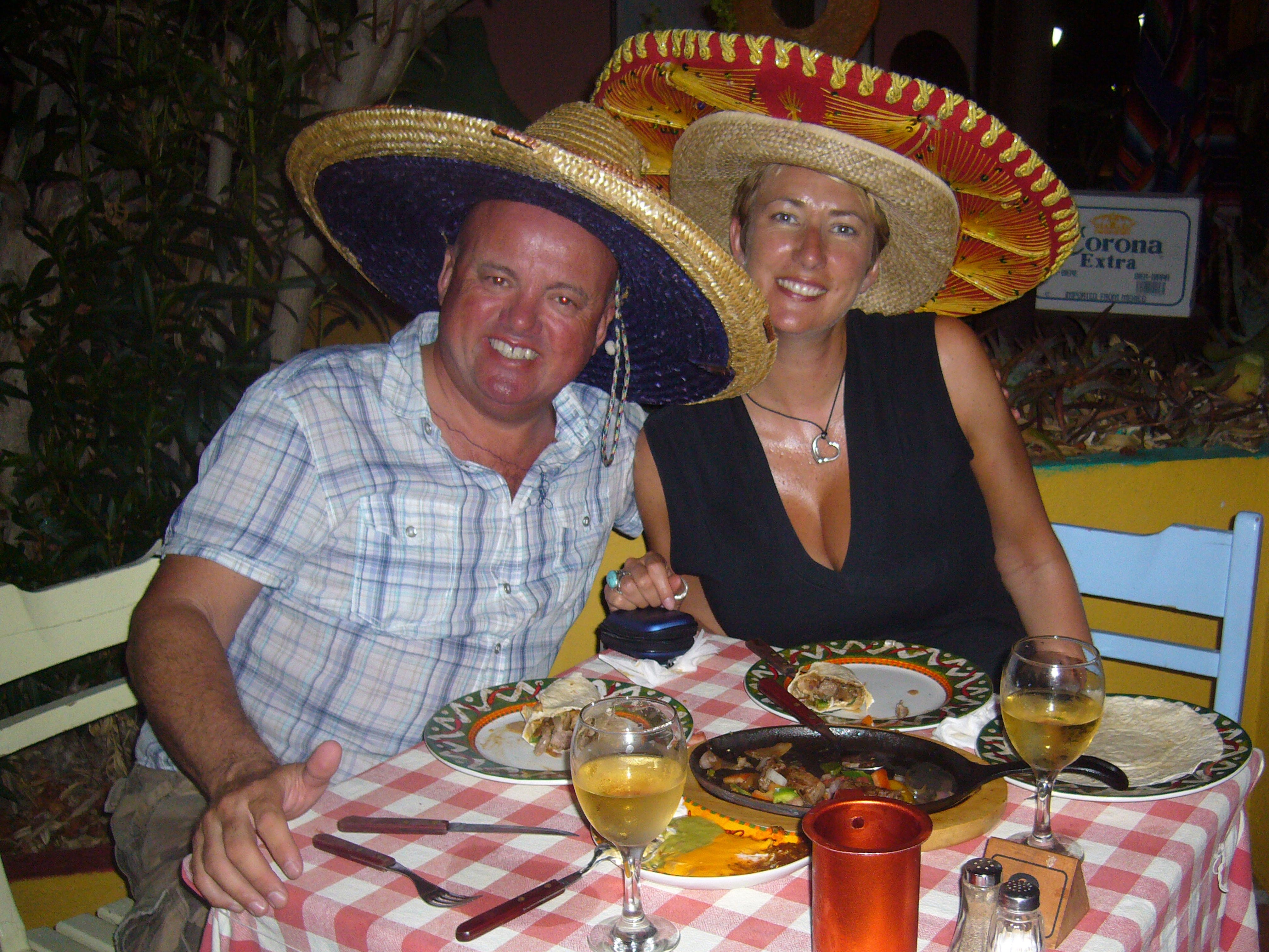 A couple sitting at a dinner table wearing sombreros