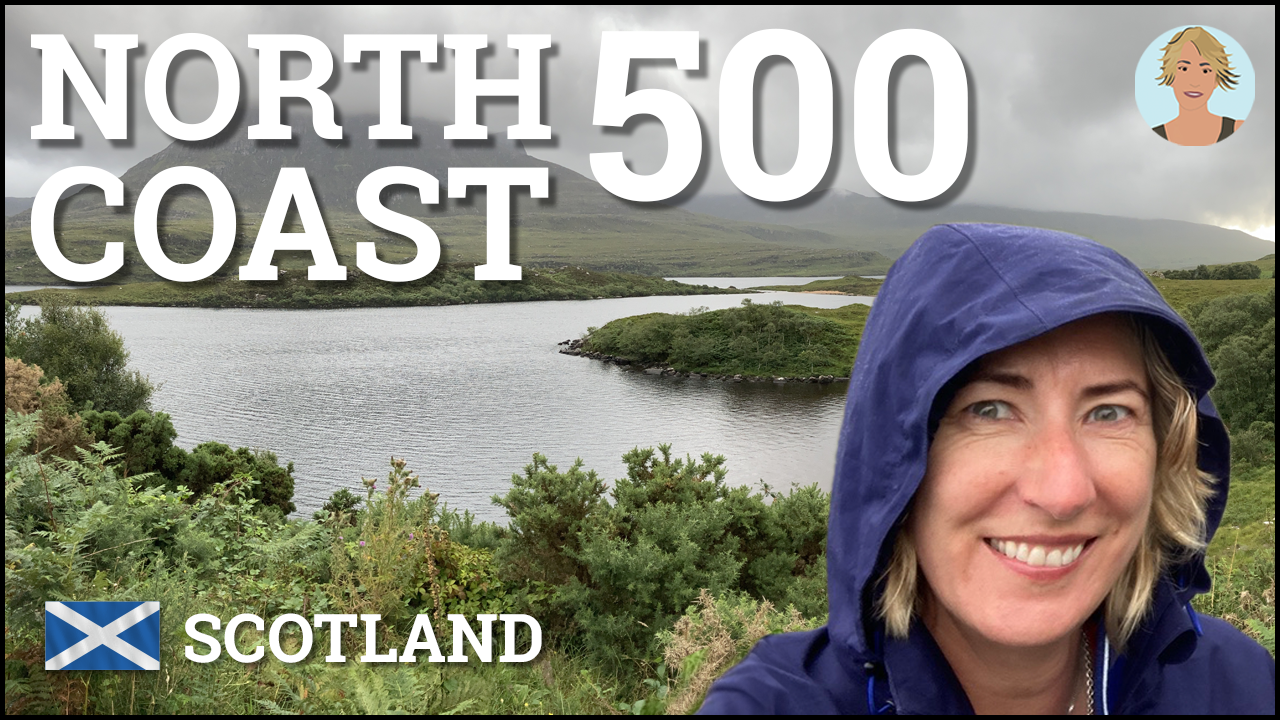 Smiling Woman in a blue coat in front of an idyllic highland scene with mountains and lakes