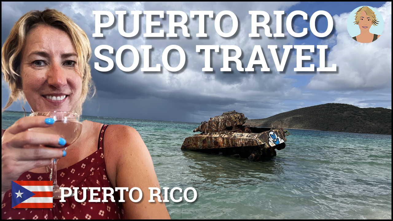 Smiling Woman in a red top sipping from a wine glass in front of an image of a rusty tank in the sea